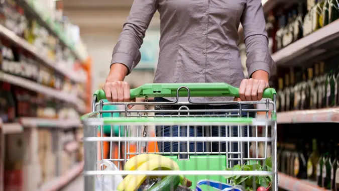 A man shopping for groceries using a cart inside a store.