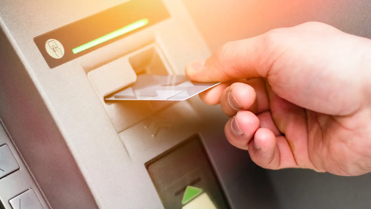 Hand of a man with a credit card, using an ATM.