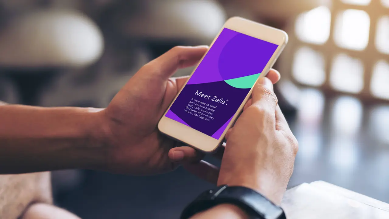 Mockup image of man's hands holding white mobile phone with blank screen in modern cafe.