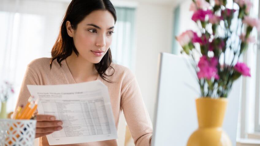 Hispanic woman paying bills on laptop.