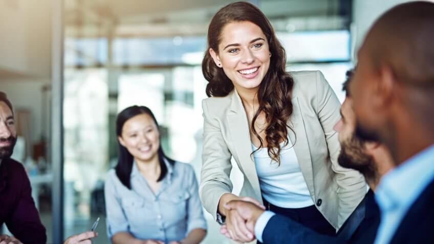 two businesspeople shaking hands during a meeting in the boardroom