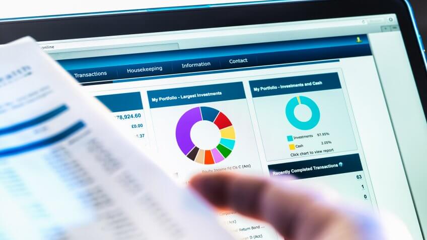 Investor checking performance of financial portfolio online whilst reviewing investment statement.