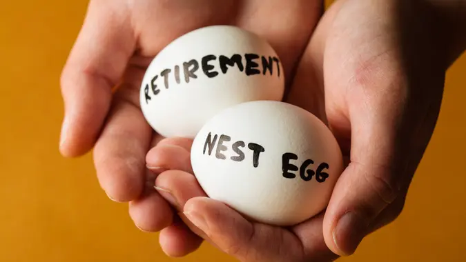 Hands Holding Two Eggs Marked Retirement And Nest Egg.