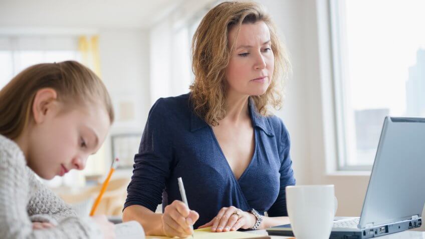 Caucasian mother and daughter working at desk.