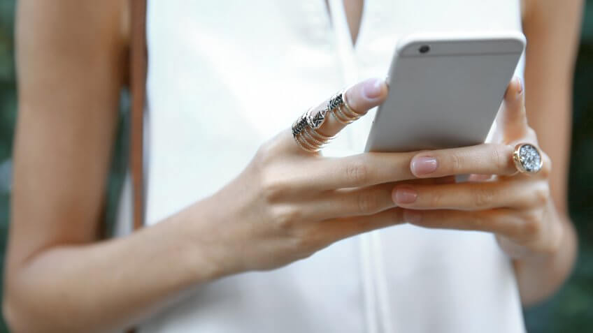 Female hands with phone and stylish rings, closeup.