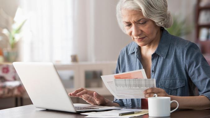 Older Black woman paying bills on laptop.