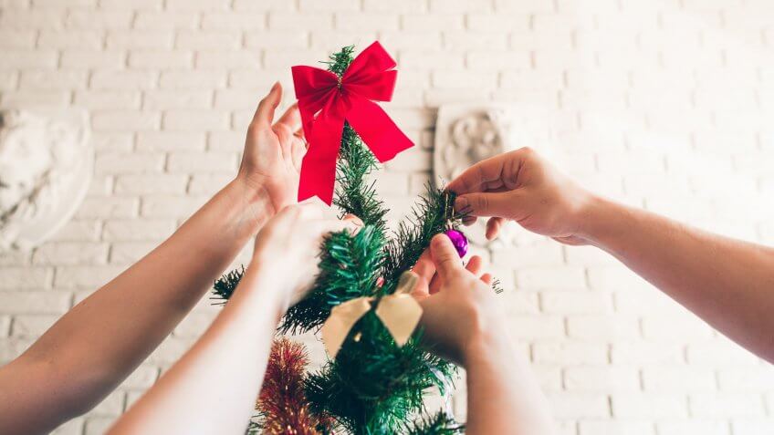Happy family decorating Christmas tree, close-up.