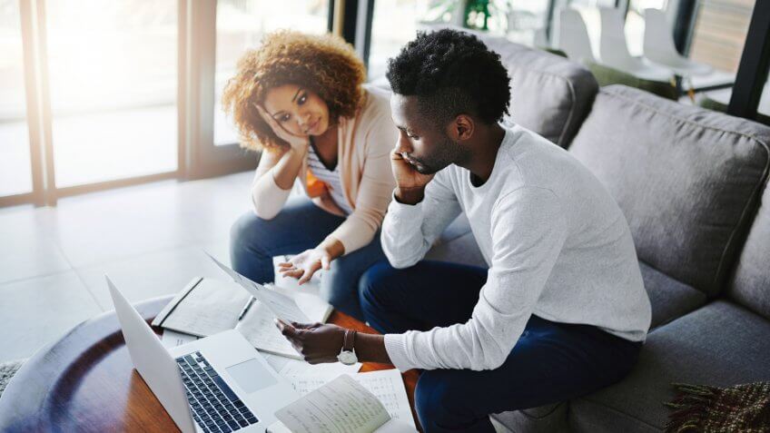 Shot of a young couple looking anxious while doing their budget at home.