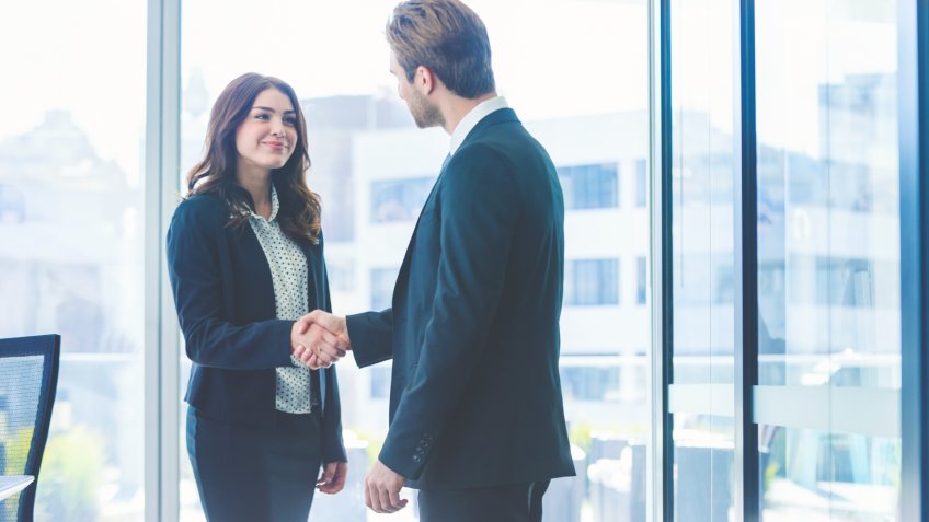 Businesswoman and businessman shaking hands.