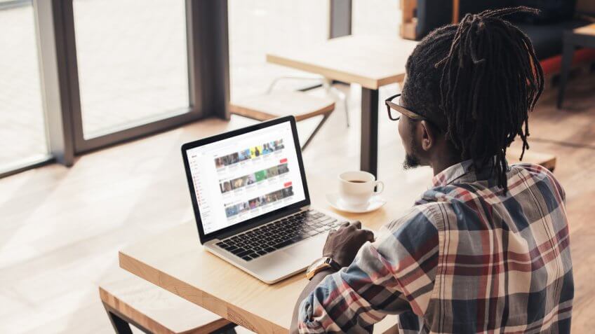 african american man using laptop with youtube website in coffee shop.
