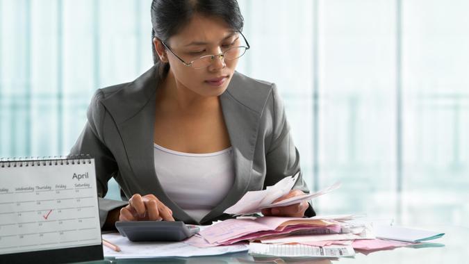 Finishing calculation for tax form on April 15 concept, with calendar in front of an accountant.