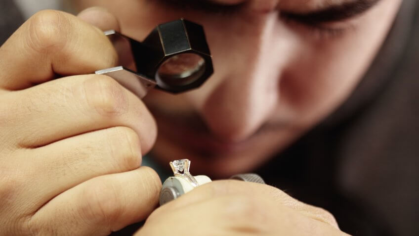 Jeweler repairing diamond ring in workshop.