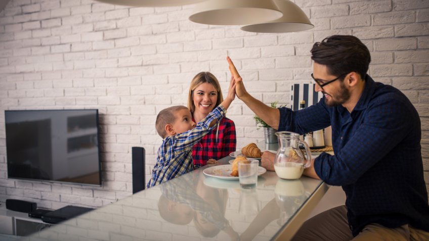 Giving high five to daddy while eating in the kitchen.