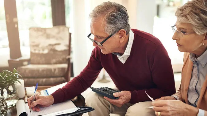 elderly couple working out a budget while sitting on the living room sofa
