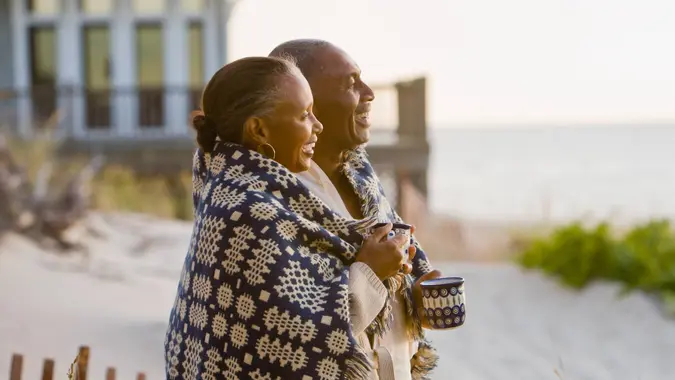60-65 years, 65-70 years, Beach, Blanket, Boyfriend, Coffee, Color Image, Copy Space, Couple, Family, Food And Drink, Girlfriend, House, Husband, Laughing, Leisure Activity, Love, Mug, Outdoors, Photography, Relaxation, Senior Adult, Side View, Smiling, Standing, Sunrise, Sunset, Travel, Two People, Waist Up, Weekend Activities, Wife, anniversary, babyboomer, cuddling, enjoying, friend, happy, man, men and women, nature, ocean, people, profile, recreation, resort, retirement, romance, together, vacation, woman