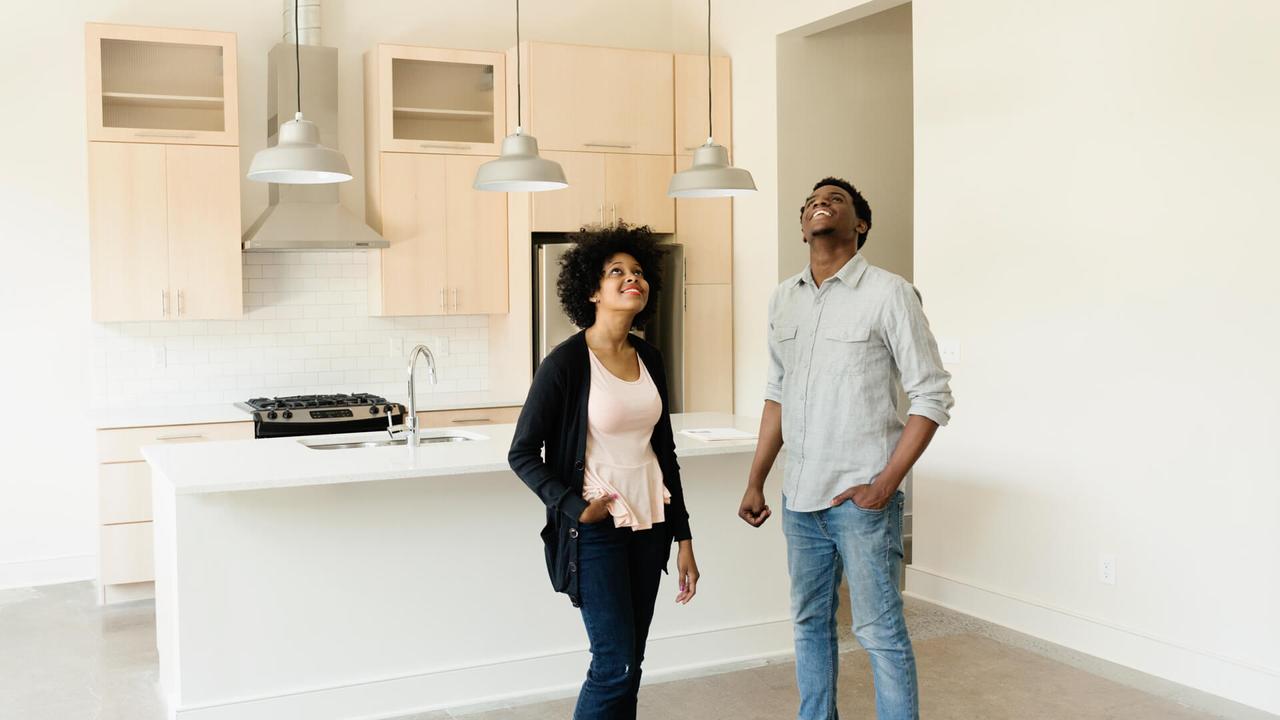 Couple standing in kitchen in new house.