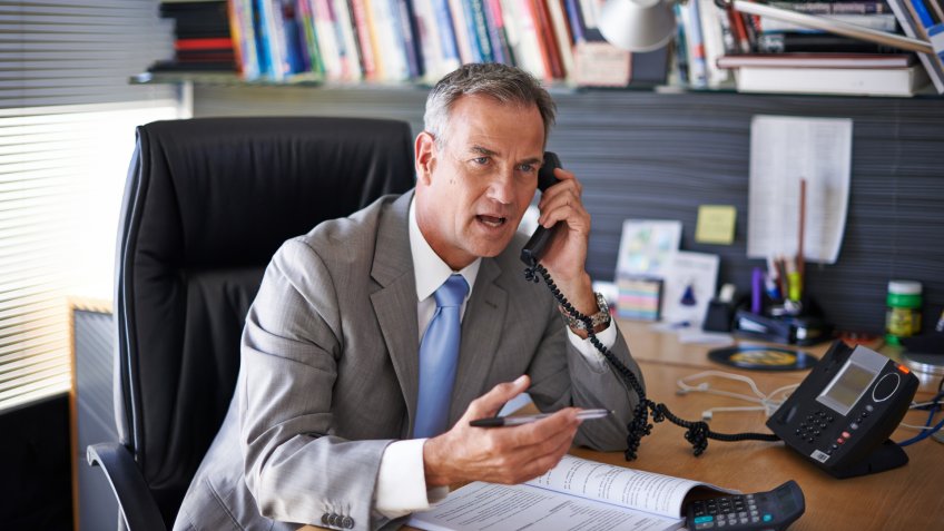 Shot of a mature businessman looking displeased while talking on the phone in his office