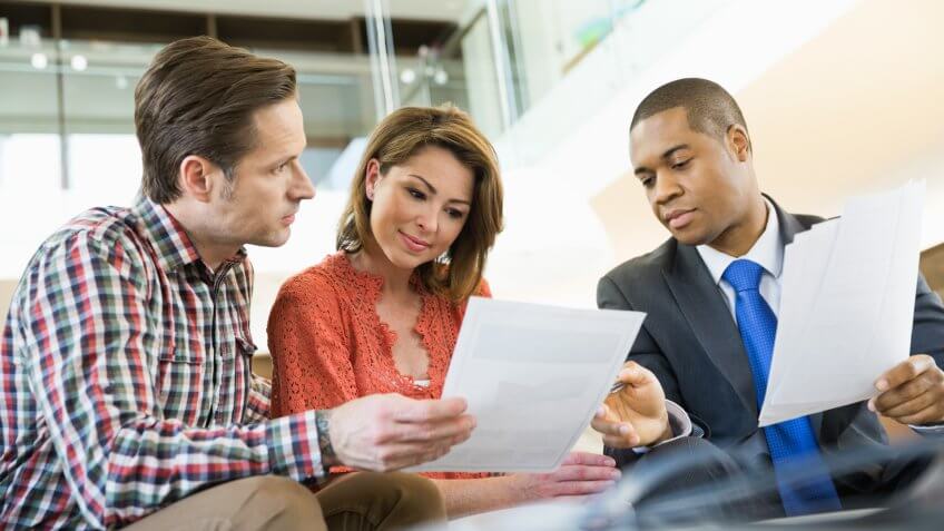 Couple reviewing paperwork with financial advisor.