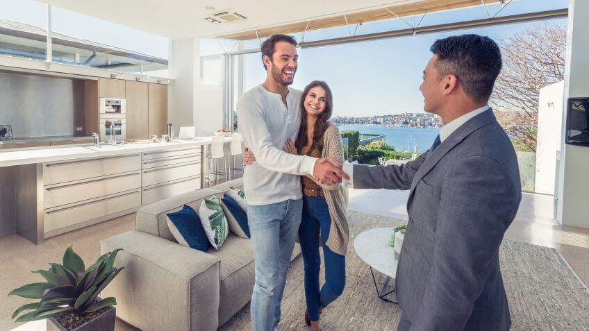 Real estate agent with couple in luxury home.