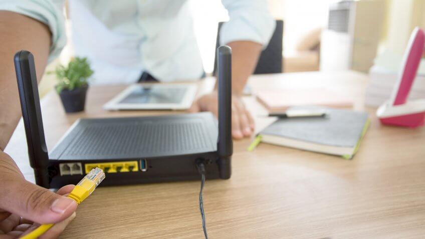 hand and lan network cable with people work on wireless router