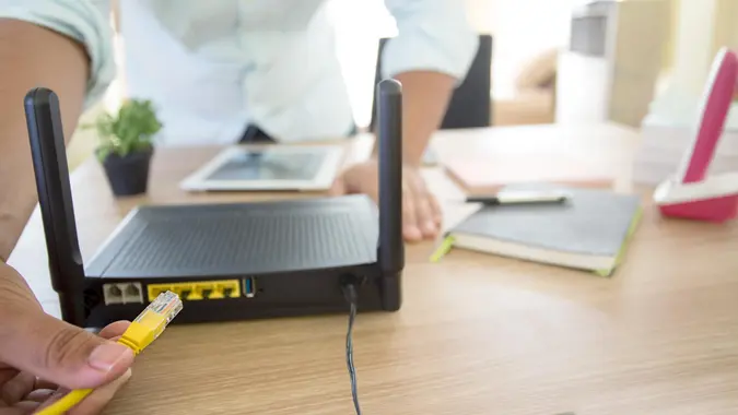 hand and lan network cable with people work on wireless router