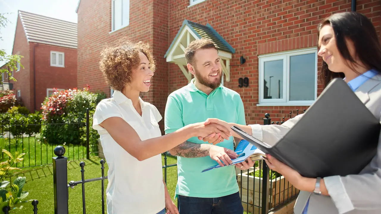 a mid adult couple celebrate receive the keys to their new house from the estate agent  .