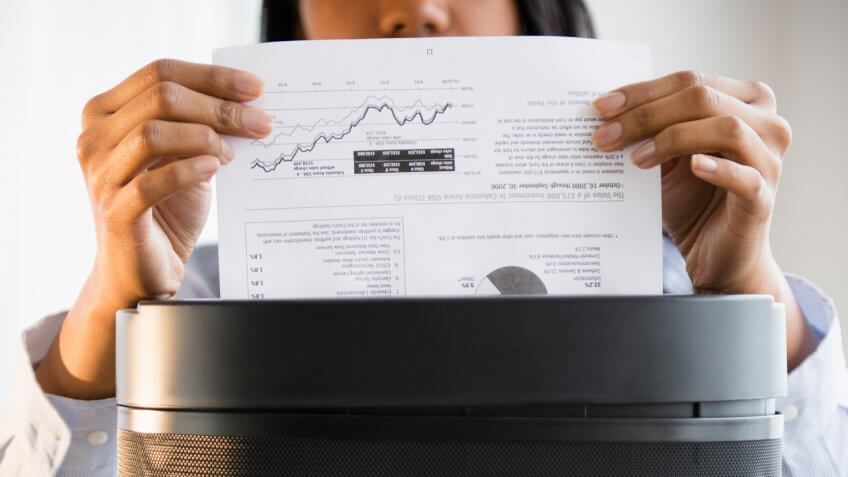Mixed race businesswoman shredding documents.