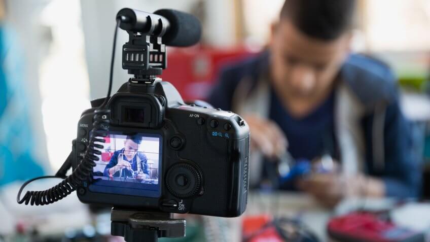 Close up camera and microphone video taping boy.