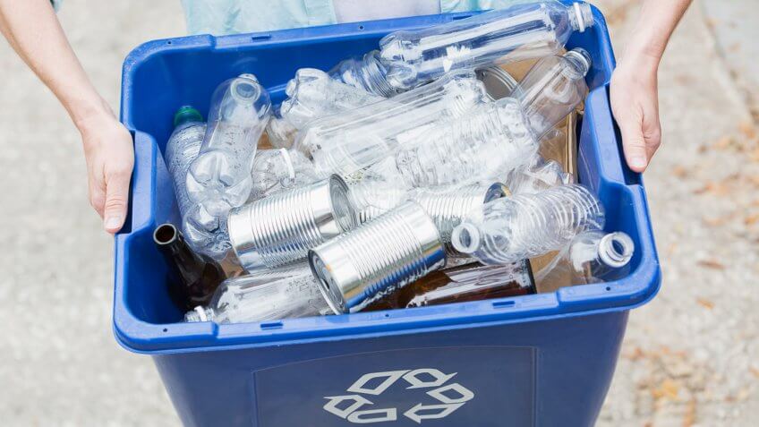 Cropped view of mature woman (40s) taking recycling bin out to the curb for collection.