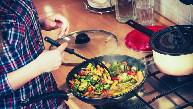 Closeup of human in kitchen cooking stir fry frozen vegetables