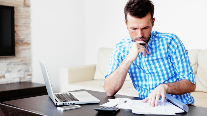 Young man paying bills at home.