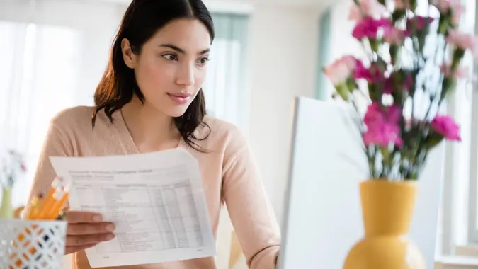 Young woman paying bills on laptop.