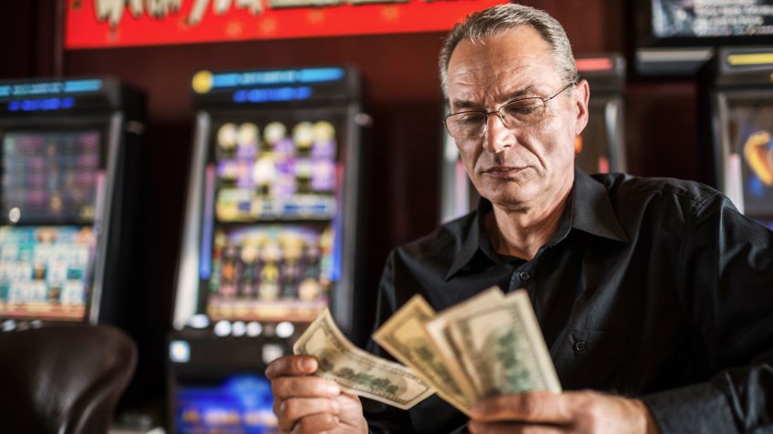 Mature man counting dollars he had won in a casino.