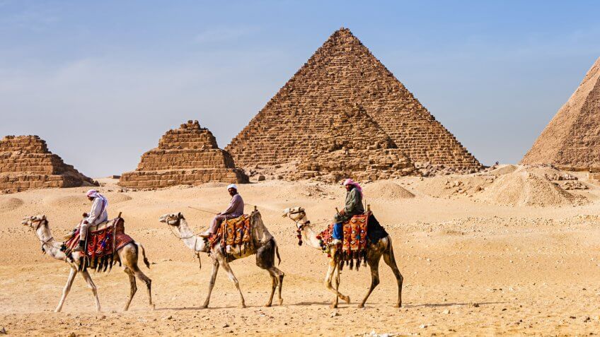 Bedouins raiding on camels, pyramids on the background, Giza, Egypt.