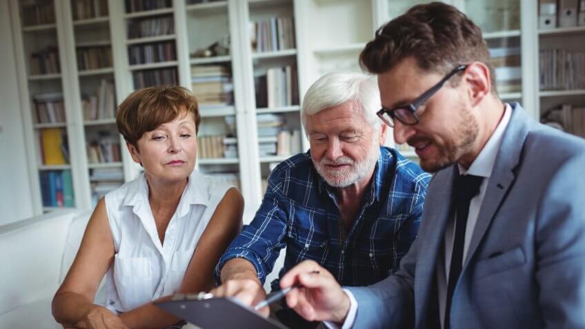 Senior couple planning their investments with financial advisor in living room.