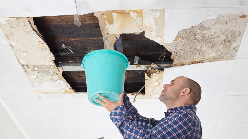 man-collecting-water-bucket-ceiling-panels