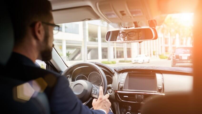 Young businessman driving to work, view over the shoulder.