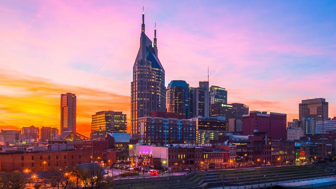 Downtown Nashville skyline with a beautiful pink, orange, and blue sunset, with the blue and pink of the sky reflected on the Cumberland River.