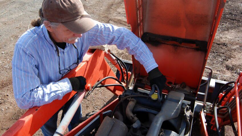 man-removing-radiator-cap-on-tractor