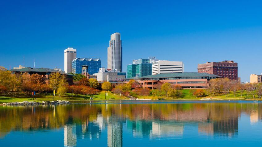 Omaha downtown skyline during Autumn, with a lake at the Heartland of America Park in the foreground.