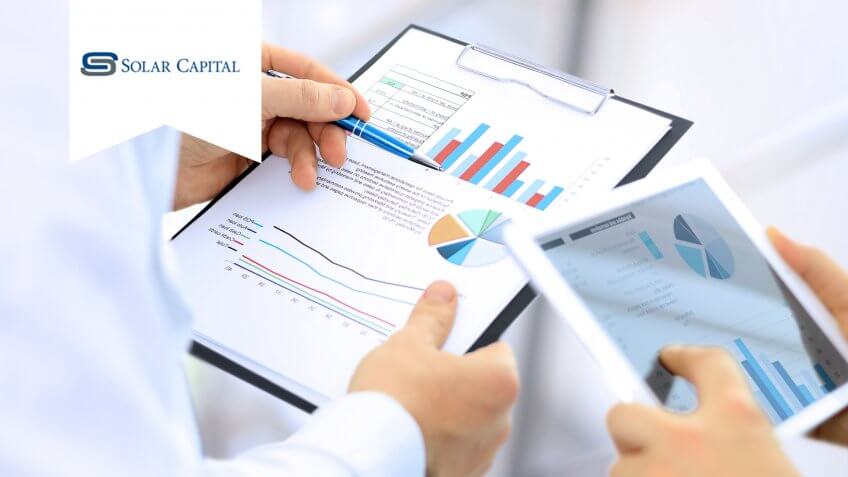 business colleagues working together and analyzing financial figures on a digital tablet and graphs.