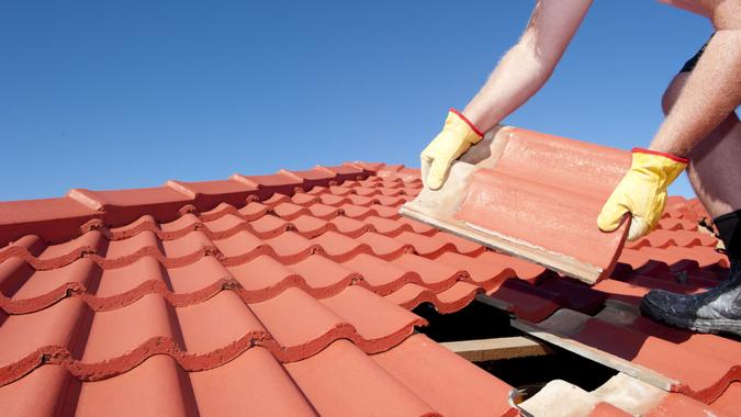 roof-repair-worker-yellow-gloves-replacing