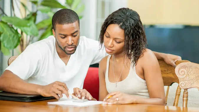 A husband and wife are sitting together at the table planning out their financial budget.
