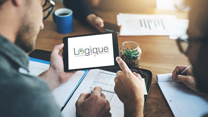 Shot of two businessmen working together on a digital tablet in an office.