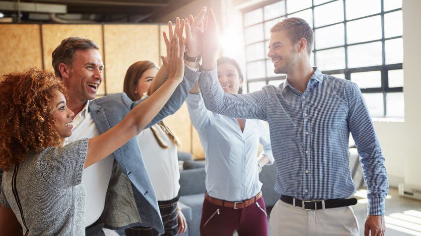 group of businesspeople high fiving in the office