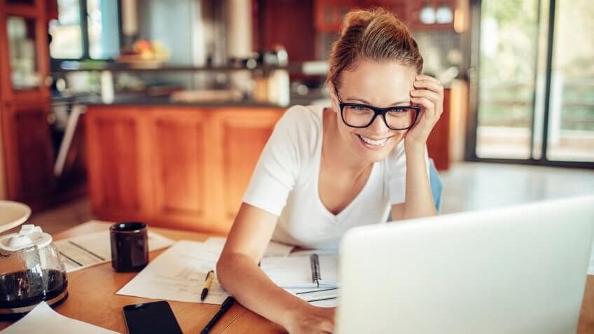 Close up of a woman using a laptop in the kitchen.