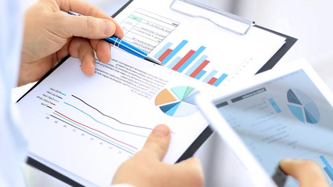 business colleagues working together and analyzing financial figures on a digital tablet and  graphs.