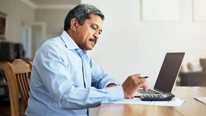 Cropped shot of a senior man using a laptop to do the household finances.