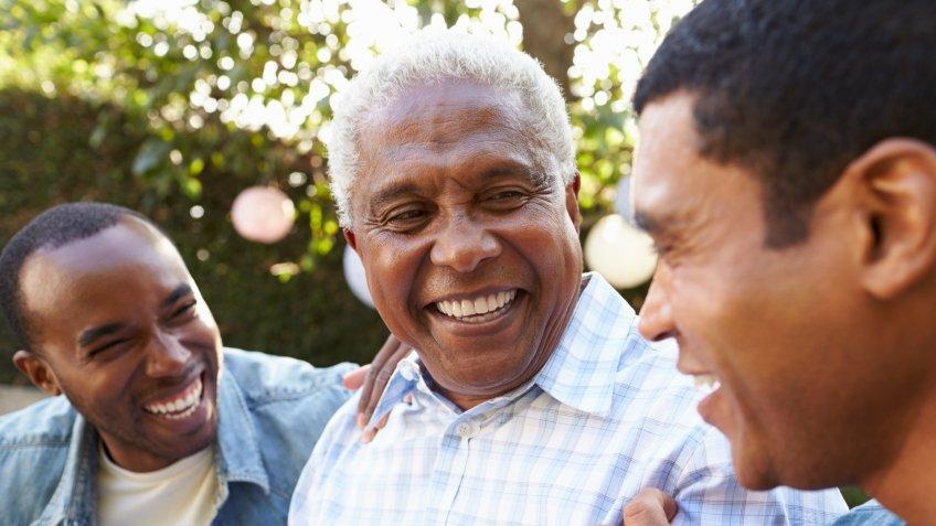Senior man talking with his adult sons in garden, close up.