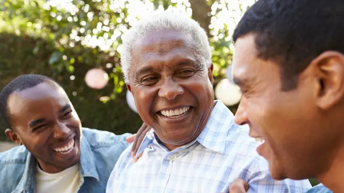 Senior man talking with his adult sons in garden, close up.